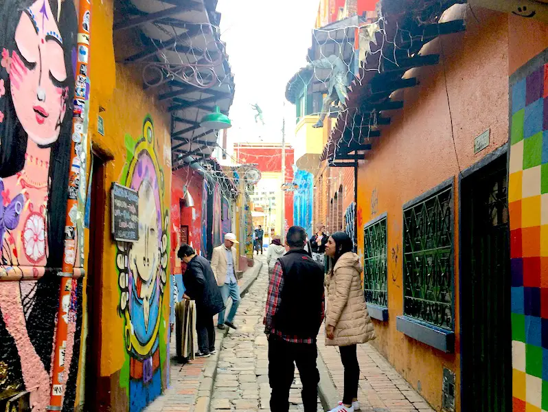 A couple walking down a narrow, colourful alleyway in Bogota, Colombia.