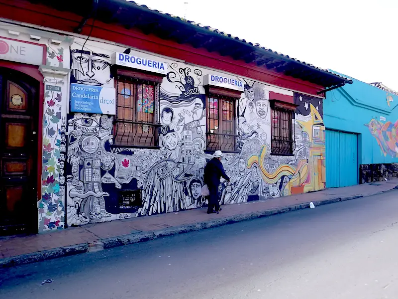 Old man walking past a graffiti decorated pharmacy in Candelaria district in Bogota, Colombia.