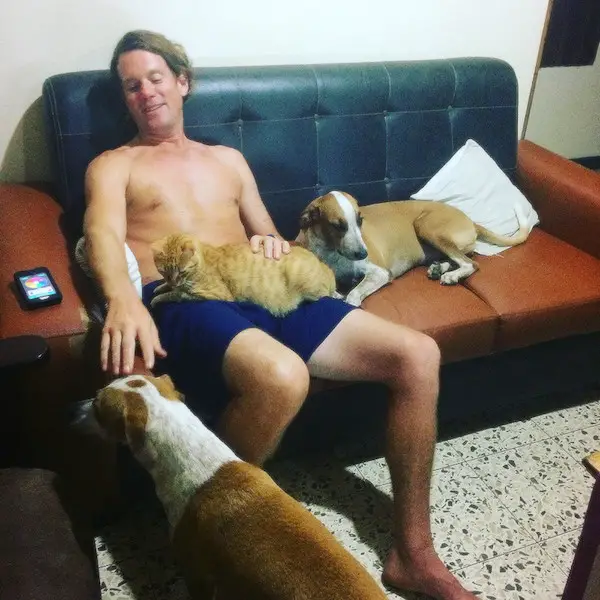Man surrounded by two dogs and a cat while housesitting in Costa Rica.