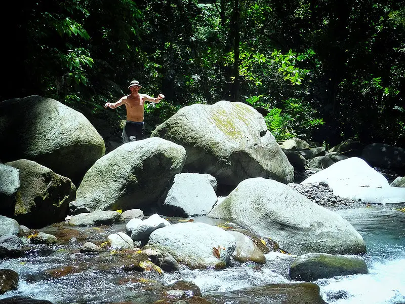 Man climbing over huge boulders in the river coming from Sari Sari Falls, Dominica