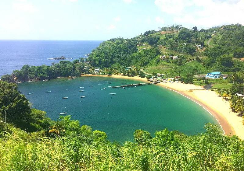 View of an emerald coloured bay with a dock and fishing boats in the water at Parlatuvier, Tobago