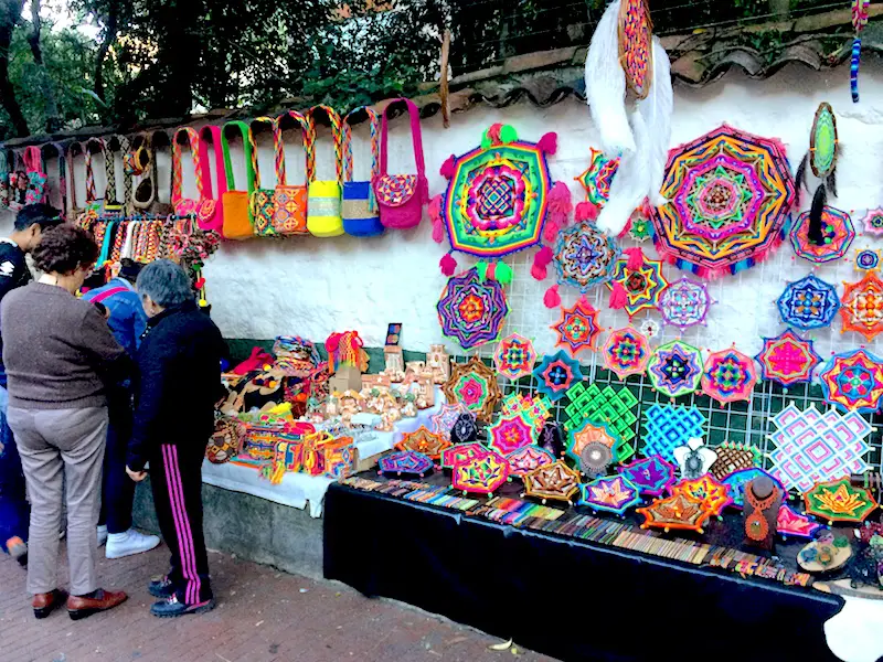 Colourful crafts hanging on a white wall in a street market in Usaquen, Bogota, Colombia