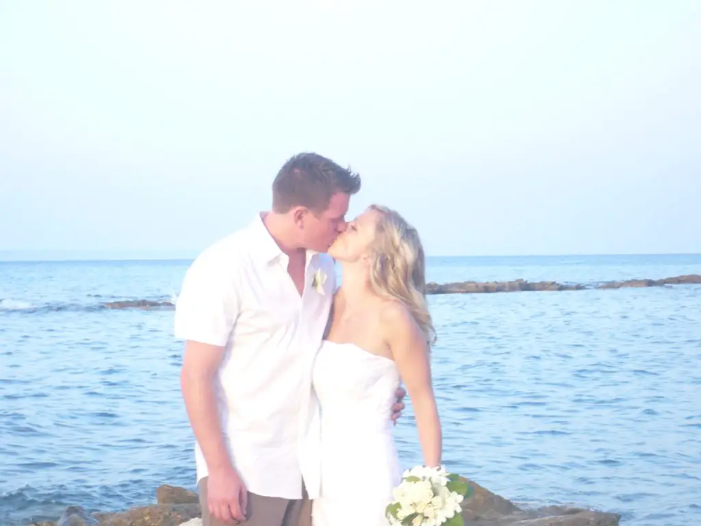 Couple kissing at their wedding with the Mediterranean Sea behind them.