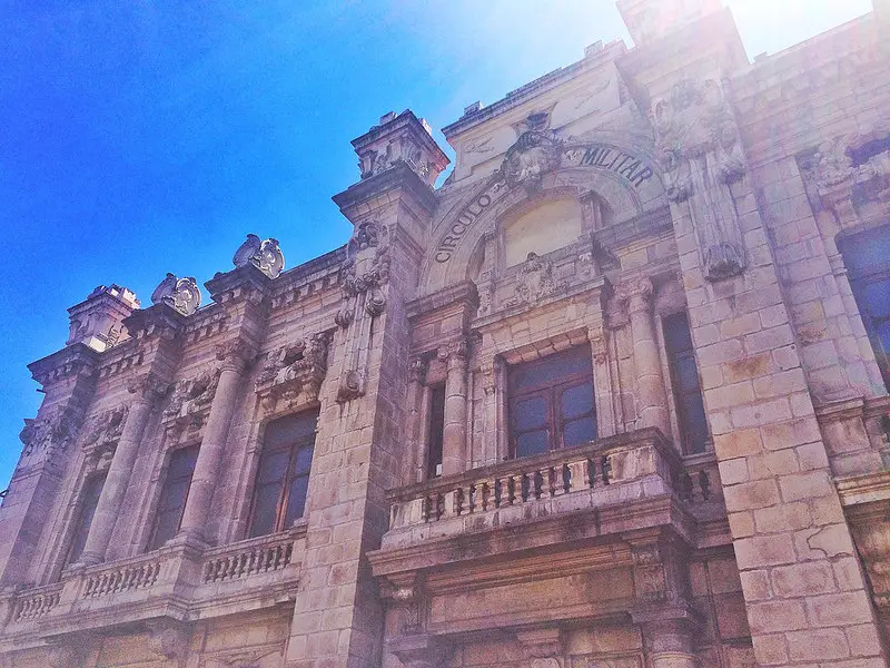 Looking up at a decorative stone building with bright blue sky above.