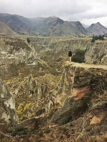 Man standing on the edge of a deep canyon in the Andes Mountains, Ecuador.