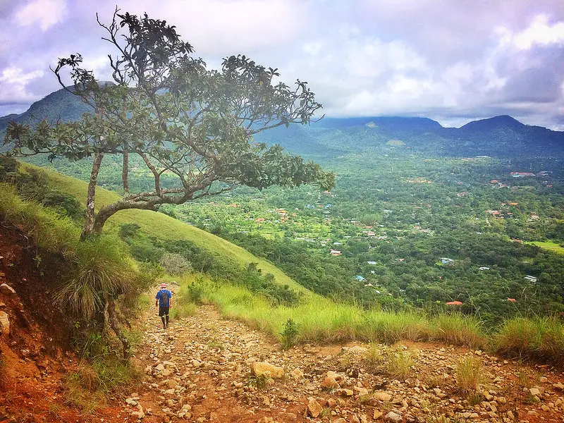 Man walking down a hiking trail with a great view across a valley to the right in El Valle, Panama.