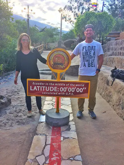 Couple straddling the red line that marks the equator near Quito, Ecuador.