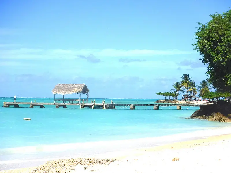 View of palapa roof on pier at Pigeon Point, Tobago with white sand and turquoise waters.