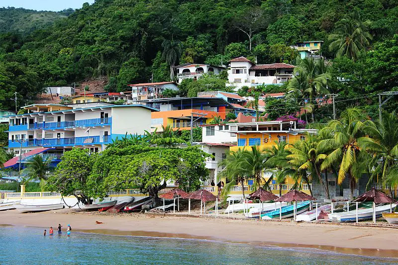 Colourful houses built into the lush hillside with fishing boats lining the beach on Taboga Island, Panama.