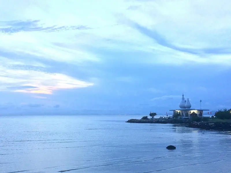 sunset over the water with a temple out on a peninsula