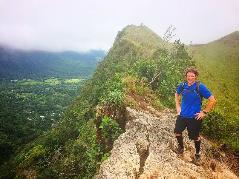 Man standing on rock ledge at top of volcanic crater, La India Dormida hike, El Valle, Panama