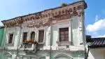 Colonial building with crumbling green paint and plant pots on the balcony in Quito Old Town, Ecuador.