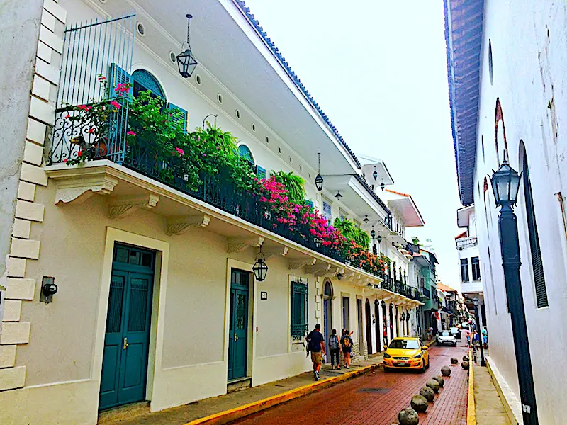 Colonial building with balcony covered in flowers on red cobblestone road in Casco Viejo, Panama City, Panama.