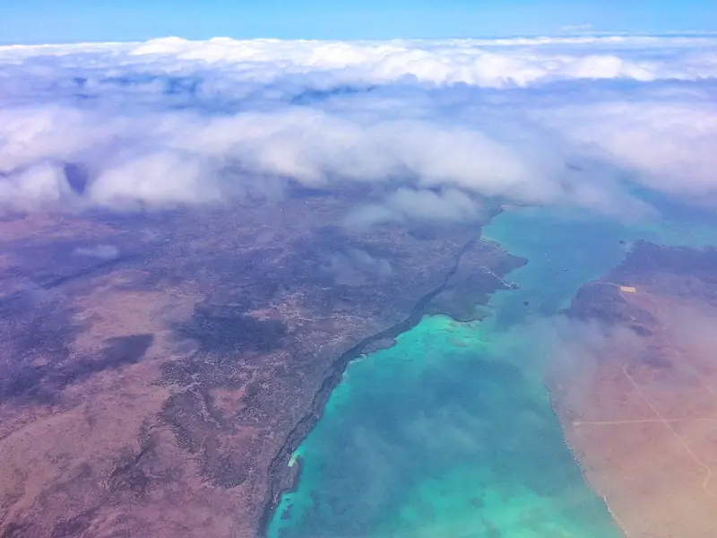 Galapagos Islands and bright turquoise waters through the clouds from a plane.