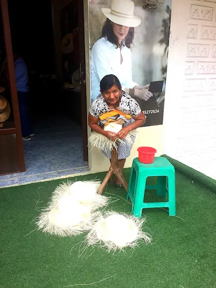 Elderly lady leaning on a traditional Panama hat as she weaves the edges in Montecristi, Ecuador