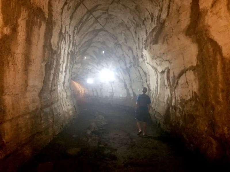 Man walking through a dark lava tube - a tunnel made from hardened lava rock on Santa Cruz island, Galapagos.