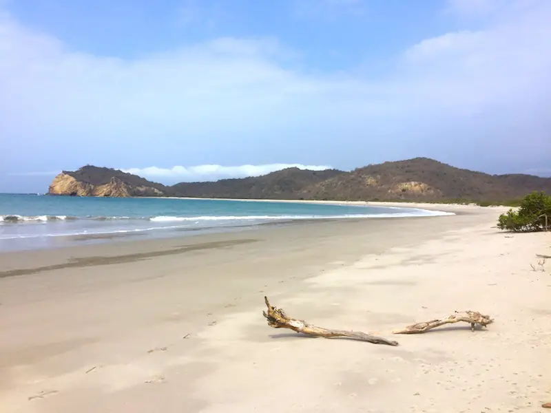 The wide sweeping bay with white sand and blue water of Playa los Frailes, Ecuador.