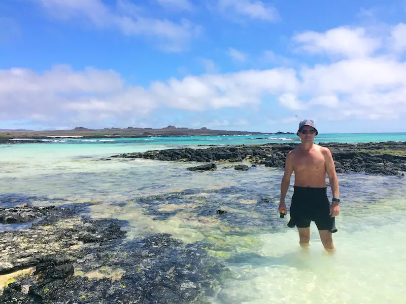 Man in knee deep clear water on a beautiful tropical beach in Galapagos Islands, Ecuador.