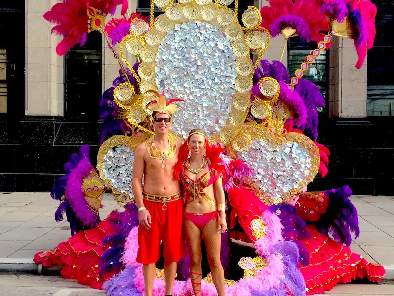 Couple in carnival costume standing in front of elaborate float, Trinidad.