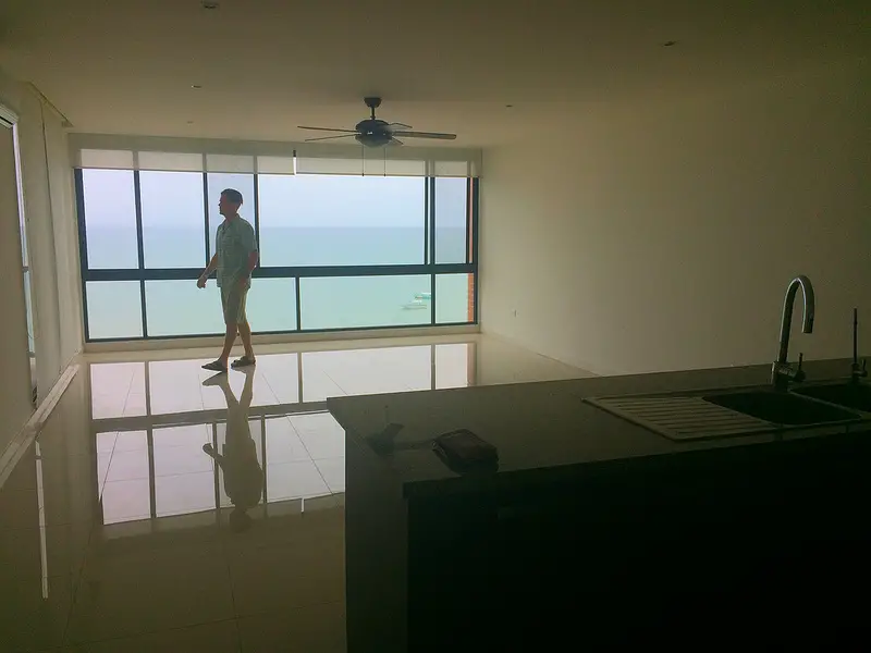 Man walking past the windows of an empty condo with sea views in Manta, Ecuador