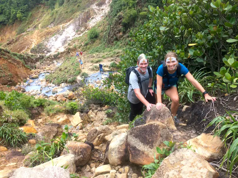 Couple hiking through a rugged valley of volcanic activity in Dominica.