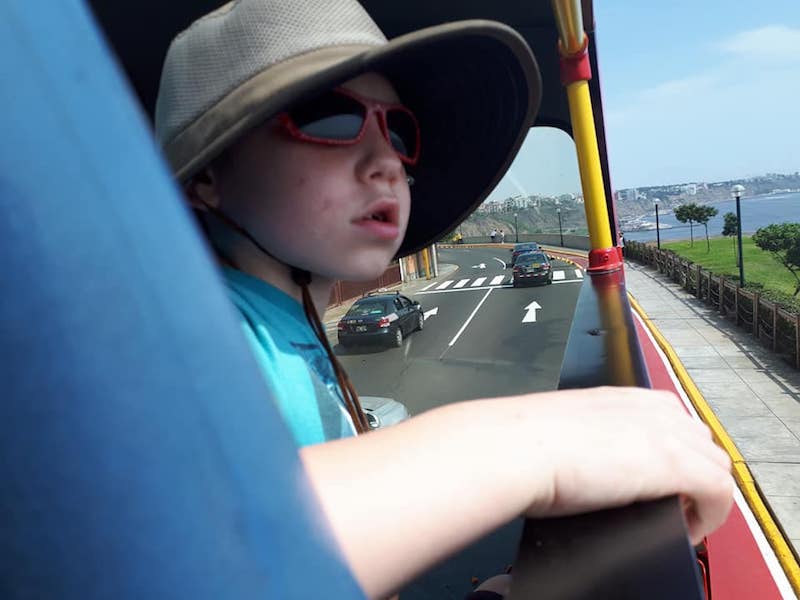 Young boy looking over the side of an open top bus along Lima's malecon.