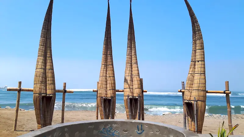 Long pointed canoes made from reeds standing up along the beach in Huanchaco, Peru.
