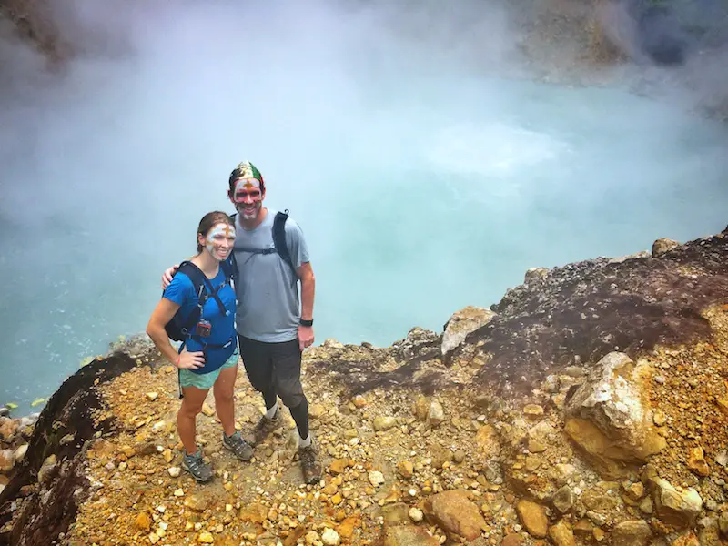Couple standing on the edge of a boiling lake in Dominica.
