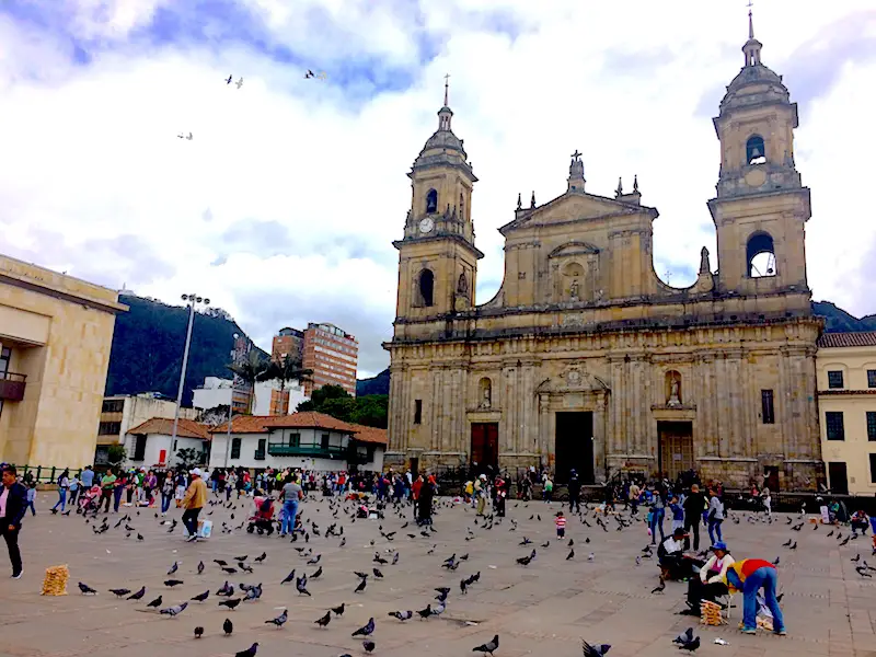 Grand cathedral with a huge plaza filled with people and pigeons in Bogota, Colombia.