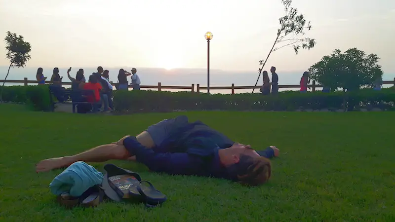 Man stretching on a strip of grass along the malecon in Lima, Peru