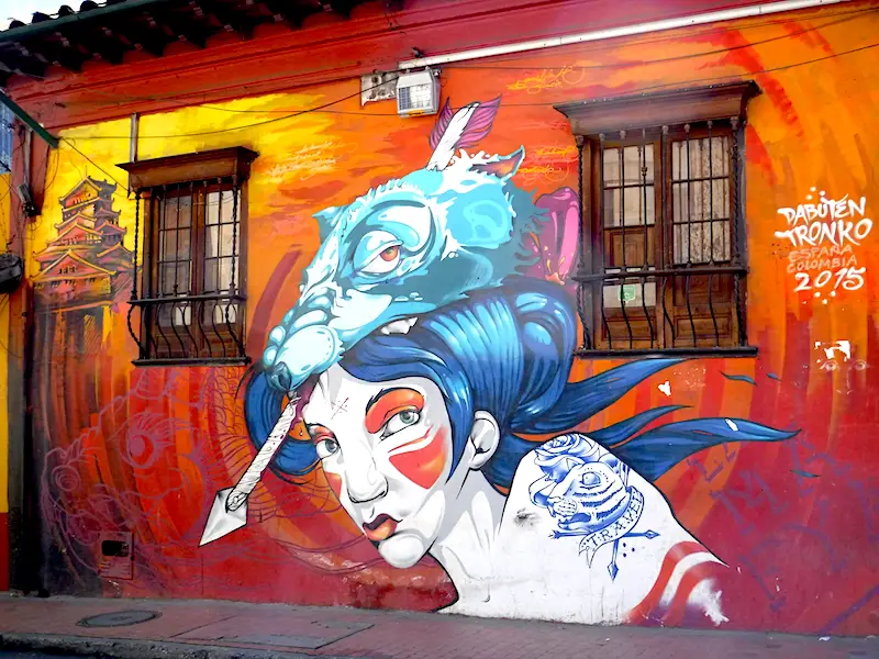 Street art of a girl with alien on her head and a red background in Bogota, Colombia.