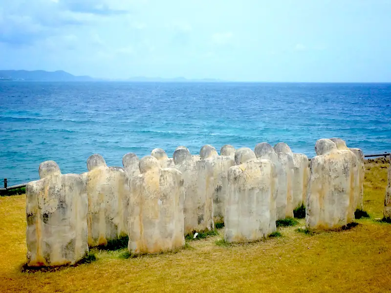 Slave statues at Anse Caffard looking out at the blue Caribbean Sea in Martinique.