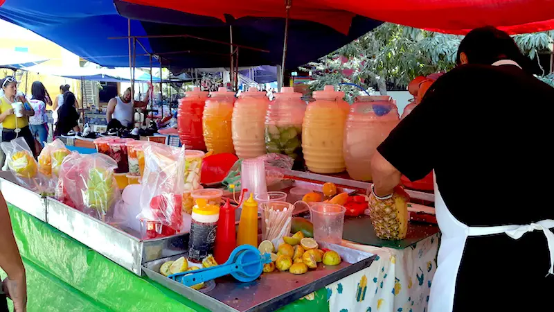 Rows of clear plastic containers filled with various fruits at a market stall in Bucerias, Mexico.