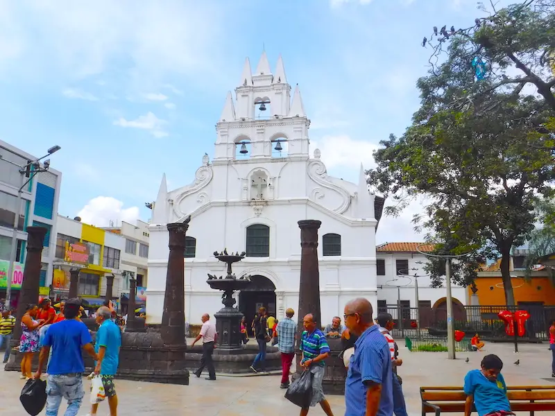 White traditional church in a busy plaza in Medellin, Colombia.