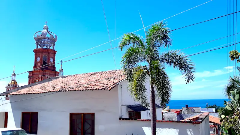 Red tiled roofs and top of cathedral with glimpse of the Pacific Ocean in Puerto Vallarta, Mexico.