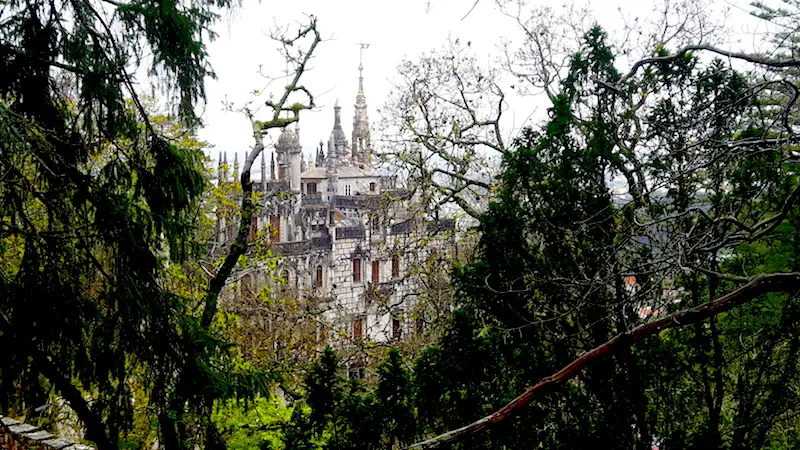 Detailed old castle with many turrets through trees in Sintra, Portugal.