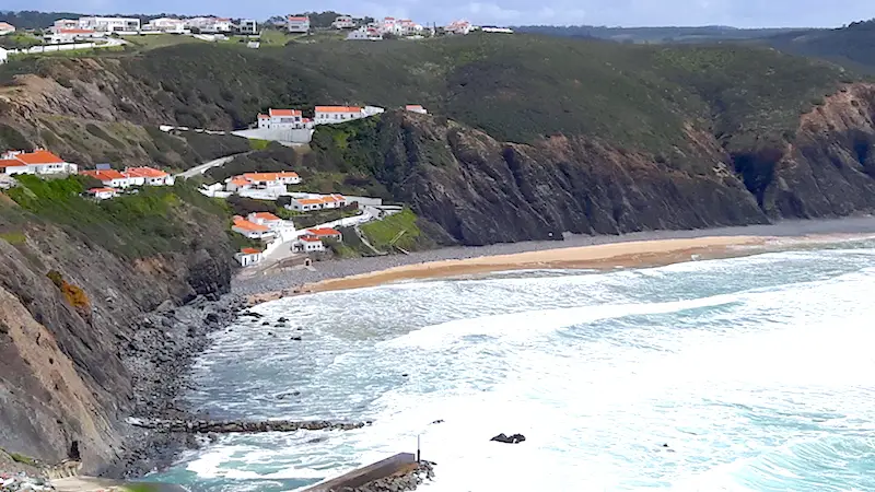Small village on a cliffside with surfing beach at the bottom in Portugal.