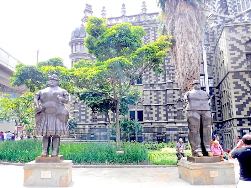 Man and woman Botero sculptures in front of ornate building in Medellin, Colombia.