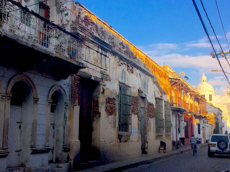 Colonial buildings in the shade with a church spire at the end of the street in Santa Marta, Colombia.