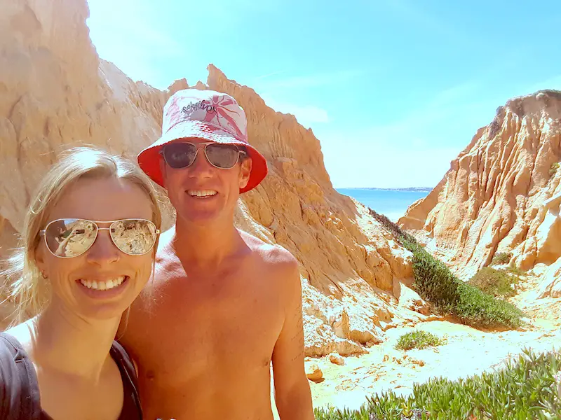 Couple standing in a ravine cut through orange sandstone with the ocean behind in Portugal.