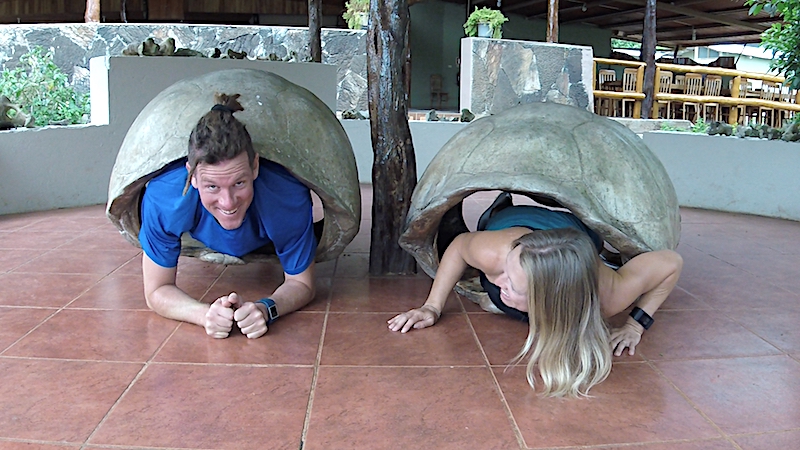 Man and woman inside giant tortoise shells, in Galapagos Ecuador