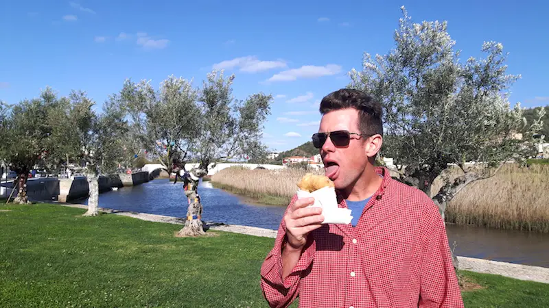 Man eating a deep fried snack in a river park in Silves, Portugal.