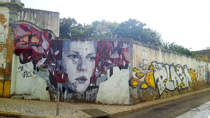 Wall covered in street art of a girl's face in Lagos, Portugal.