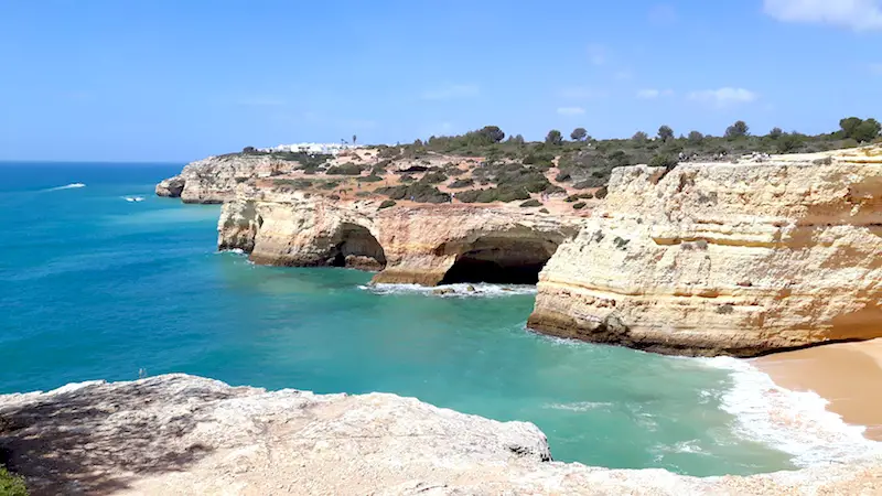 Caves and bays in cliff formations with turquoise water below in Algarve Portugal.