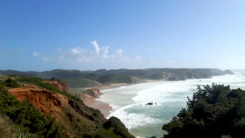 View between cliffs to a beach with huge waves on the Vicentina Coast of Portugal