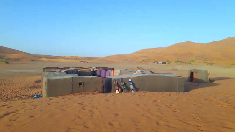 Group of square nomad tents in the middle of orange sand dunes in the Sahara desert, Morocco