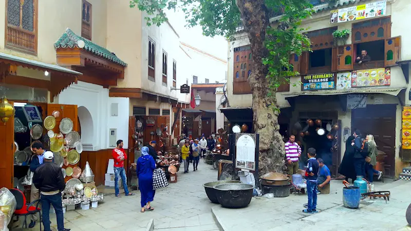 Alley of Fes Medina filled with metal workers and people walking, Morocco.