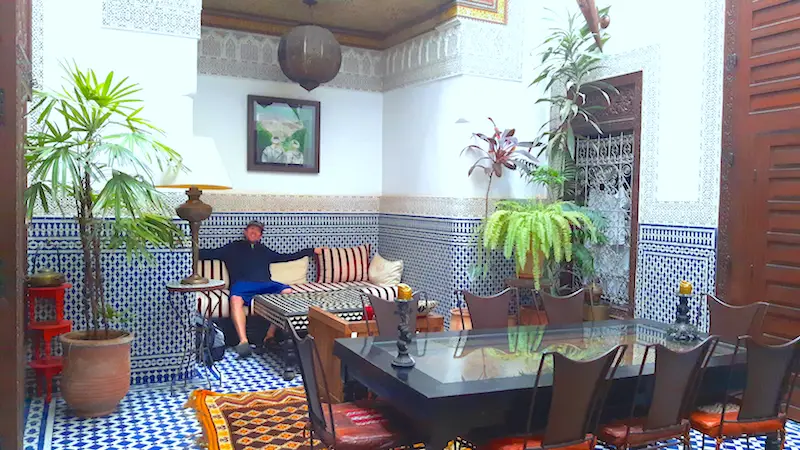 Man relaxing in a beautifully decorated living area in a riad in Fes, Morocco.