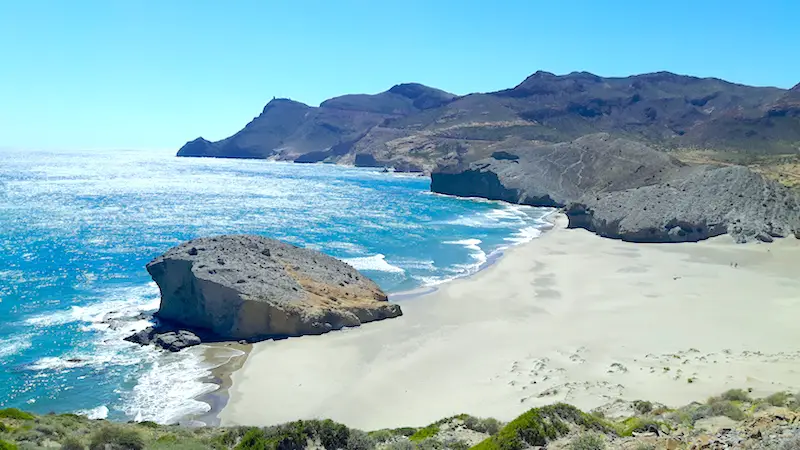 Beach surrounded by surreal shaped rocks created by molten lava, Playa de Monsul in Cabo de Gata, Spain.