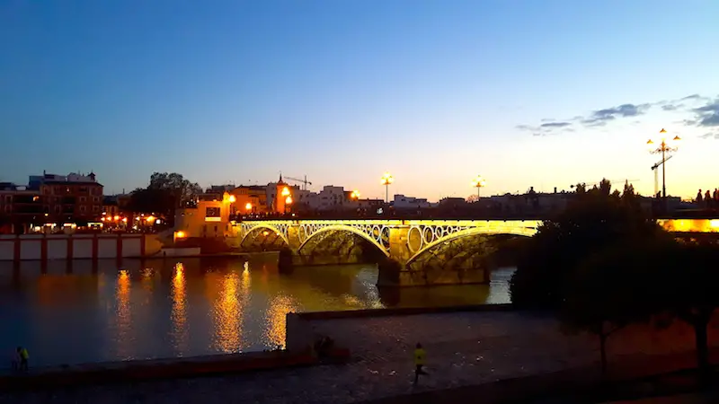 Bridge over the river lit up at dusk in Seville, Spain.
